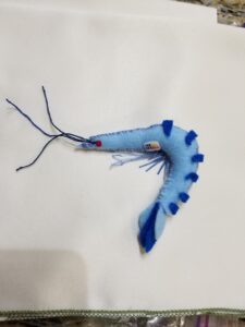 A small blue plushie of a prawn with an Imperial Navy insignia on his chest, a Star Wars joke